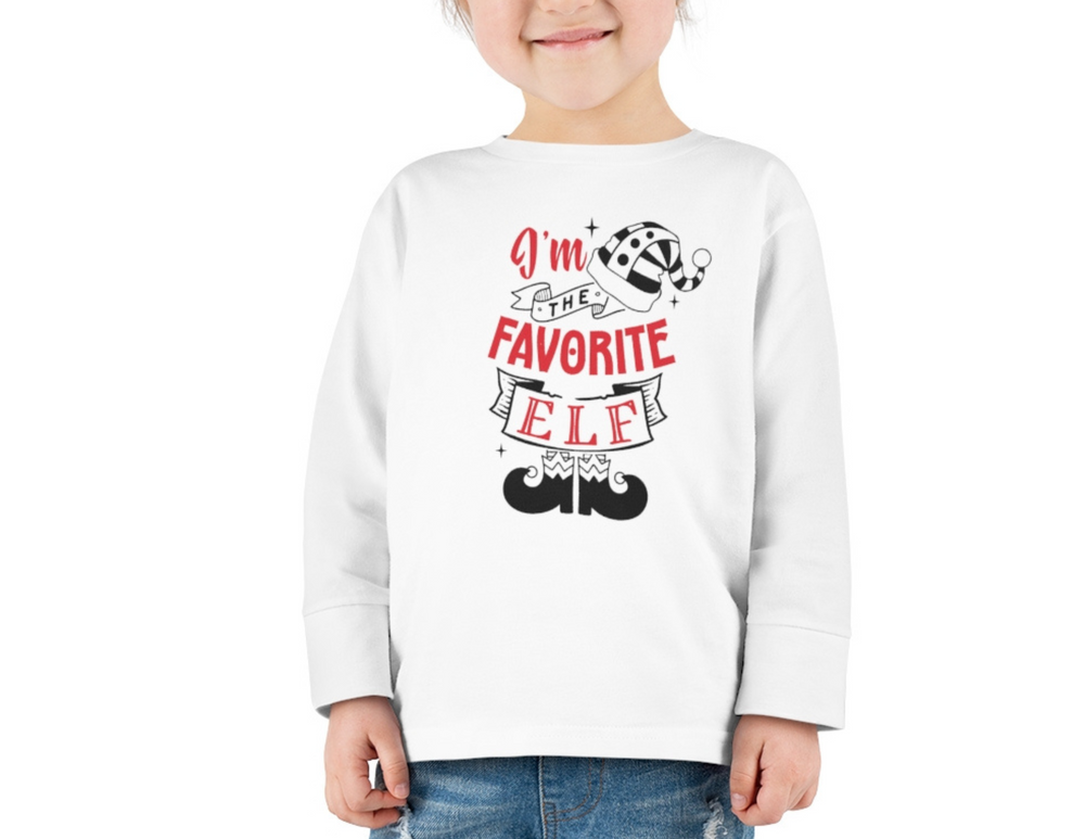 Toddler long sleeve tee featuring I'm the Favorite Elf design. 100% Airlume combed cotton for comfort. Image: child in white shirt. Store: 'Worlds Worst Tees'.