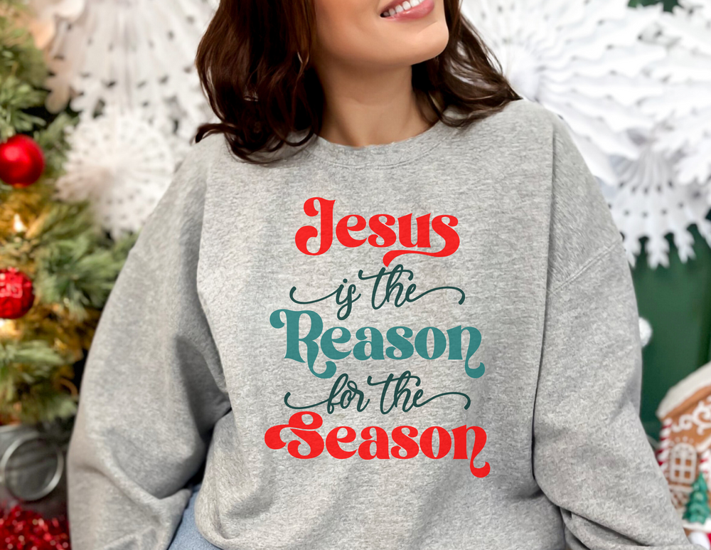 A woman smiling in a grey sweatshirt, embodying comfort and style with the Jesus is the Reason for the Season Crewneck. Unisex, heavy blend fabric, ribbed knit collar, and seamless design for ultimate coziness.