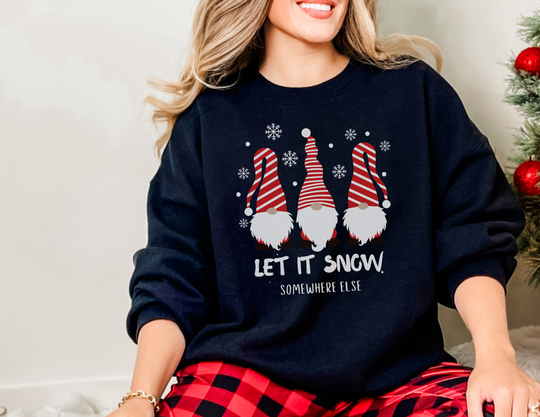 A woman in Let it Snow Somewhere Else Long Sleeve Tee, with gnomes and a snowflake. Classic fit, 100% cotton, no side seams, taped shoulders for durability. Medium fabric, runs smaller.