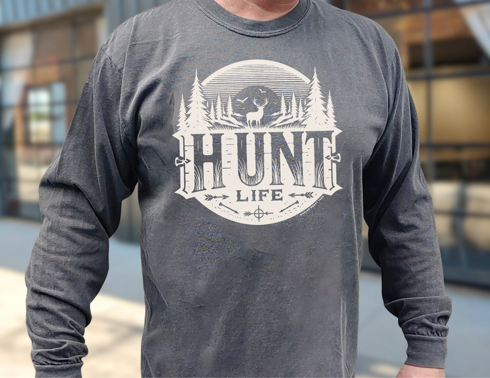 A man in a Hunt Life Long Sleeve T-Shirt, featuring a grey shirt with a white deer logo. Made of 100% ring-spun cotton for softness and style. Ideal for casual wear. From Worlds Worst Tees.