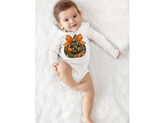 Baby wearing Jackie O Long Sleeve Onesie with camo jack-o’-lantern print, lying on a fluffy rug, smiling, showcasing soft, durable fabric and easy-change snaps.