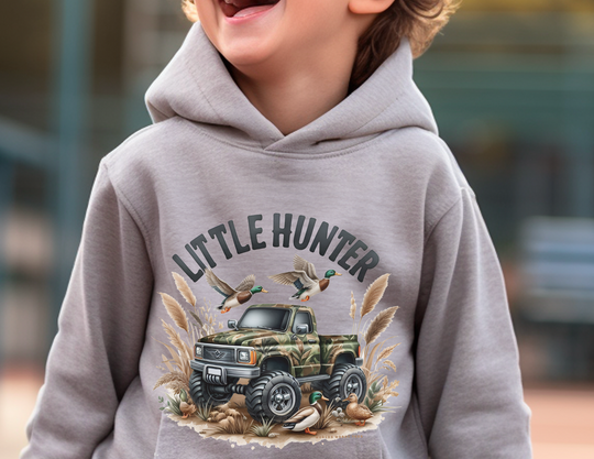 Little Hunter Toddler Hoodie featuring a child in a grey sweatshirt with a truck and ducks, designed for comfort with jersey-lined hood, cover-stitched details, and side seam pockets. From Worlds Worst Tees.