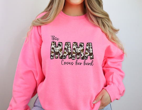 A cozy Mama Herd Crew sweatshirt in pink, featuring a ribbed knit collar for shape retention. Unisex, 50% cotton, 50% polyester blend, loose fit, and medium-heavy fabric. Ideal comfort for any occasion.