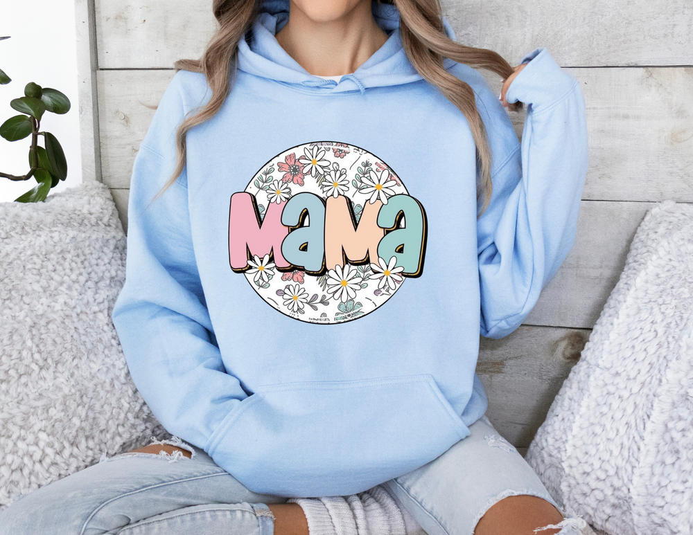A woman in a blue sweatshirt lounging on a couch, showcasing the Sassy Mama Flower Hoodie from Worlds Worst Tees. Unisex, cozy blend of cotton and polyester, with kangaroo pocket and matching drawstring.