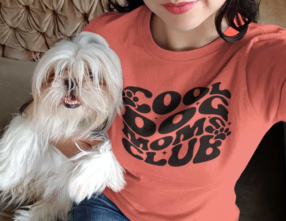 A cool Dog Mom's Club Tee in ring-spun cotton, featuring a woman holding a dog. Garment-dyed for extra coziness, with a relaxed fit and durable stitching for everyday wear.