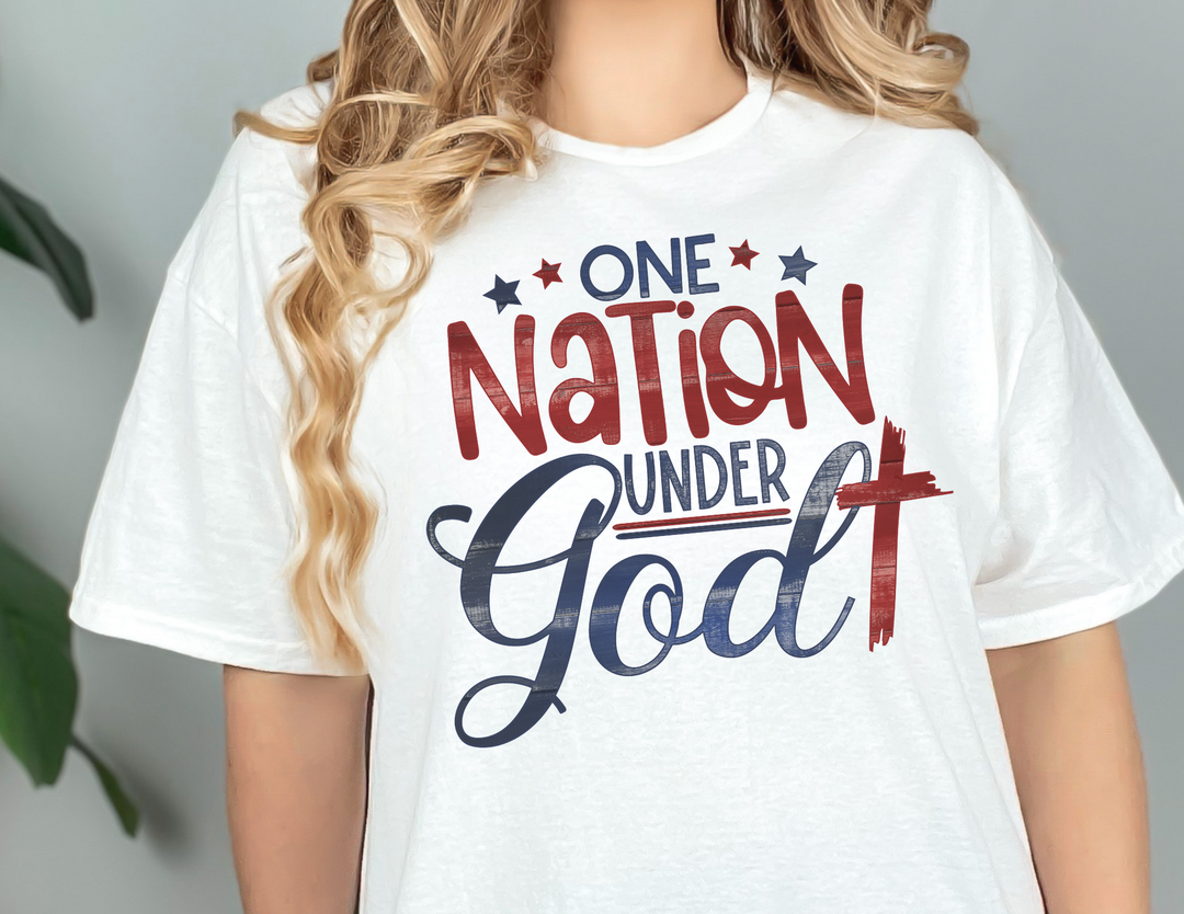 A unisex jersey tee featuring One Nation Under God text. Made of 100% cotton, light fabric, with ribbed knit collars and taping on shoulders for durability. Sizes range from XS to 3XL.