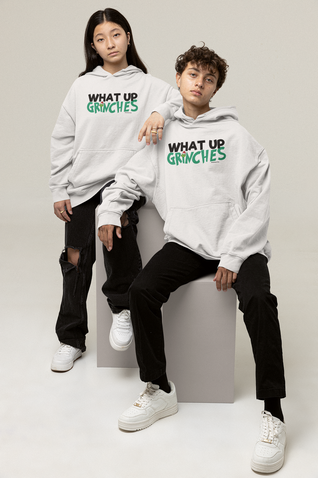 Two men in matching sweatshirts, one wearing a white shoe, showcase the What up Grinches Youth Hoodie by Worlds Worst Tees. Youth blend hooded sweatshirt with kangaroo pocket and reinforced neck.
