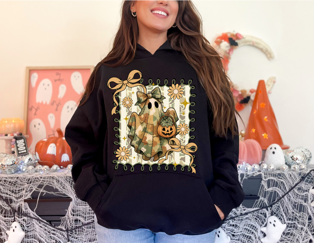 Woman wearing Quilted Ghost Hoodie with patchwork ghost design, surrounded by Halloween décor, featuring a cozy fit with kangaroo pocket and matching drawstring.