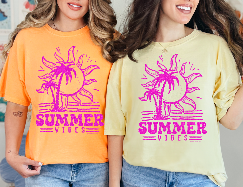 Two women in Summer Vibes Tees, one in yellow with a pink sun and palm trees, the other in orange with the same design. Garment-dyed 100% ring-spun cotton, relaxed fit, durable double-needle stitching.