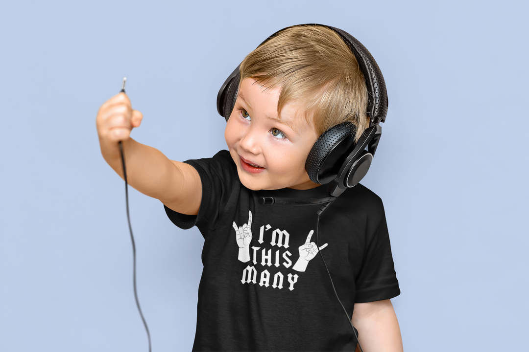 A toddler wearing headphones holds a cord, embodying the Rock and Roll I'm 4 Toddler Tee. Soft, 100% cotton tee with durable print, perfect for sensitive skin and first adventures.