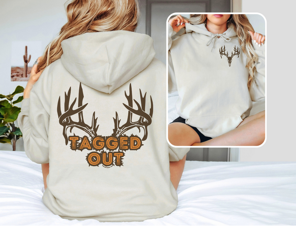A Tagged Out Sweatshirt featuring a woman in a white hoodie with antlers and text. Unisex heavy blend, 50% cotton, 50% polyester, with kangaroo pocket and drawstring hood. Classic fit, tear-away label.