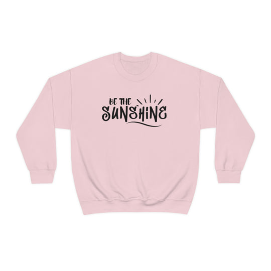 A unisex Be The Sunshine Crewneck sweatshirt in pink with black text. Made of 50% cotton, 50% polyester, featuring a ribbed knit collar and no itchy side seams. Medium-heavy fabric, loose fit, true to size.