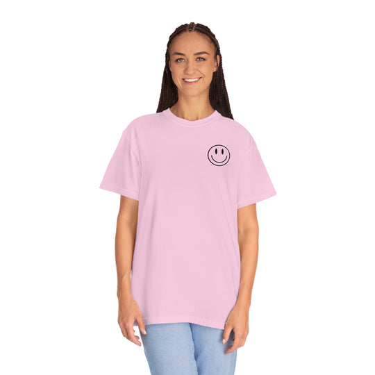 A woman in a pink Don't Forget To Smile Today Tee with a smiley face, showcasing a relaxed fit garment-dyed t-shirt made of ring-spun cotton for cozy daily wear.