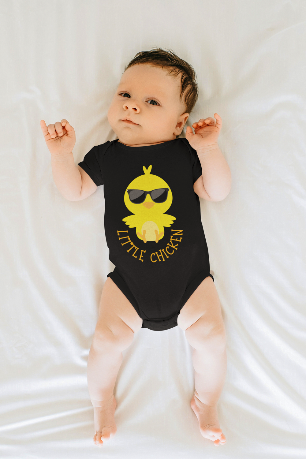 A Little Chicken Onesie for infants, featuring a baby in a black shirt with a yellow bird design. Made of soft ring-spun cotton, with lap shoulders for comfort and ease. Unisex fit, ideal for younglings.